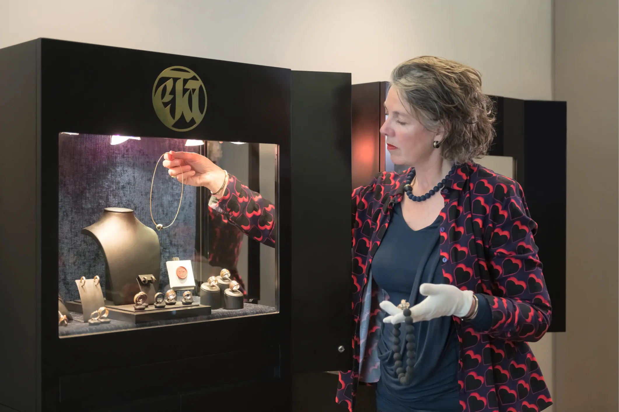 Corporate photo of a jeweller placing a piece of jewellery in a display case
