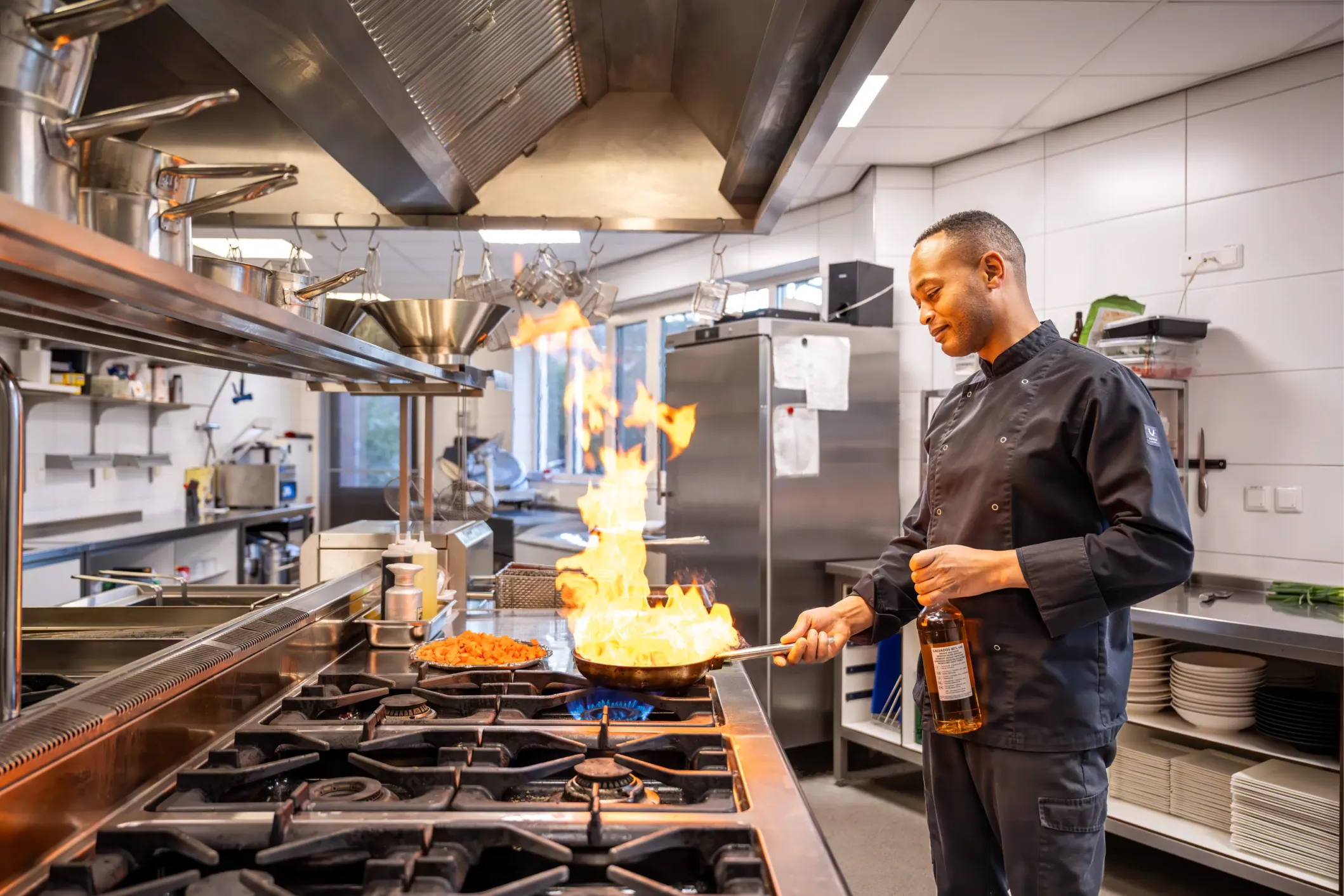 Corporate photo of a man cooking with wine as a large flame rises