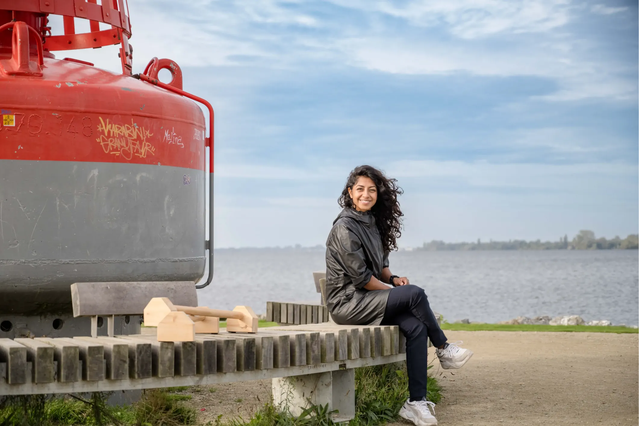 Corporate photo of a woman on the coast, seated on a round bench