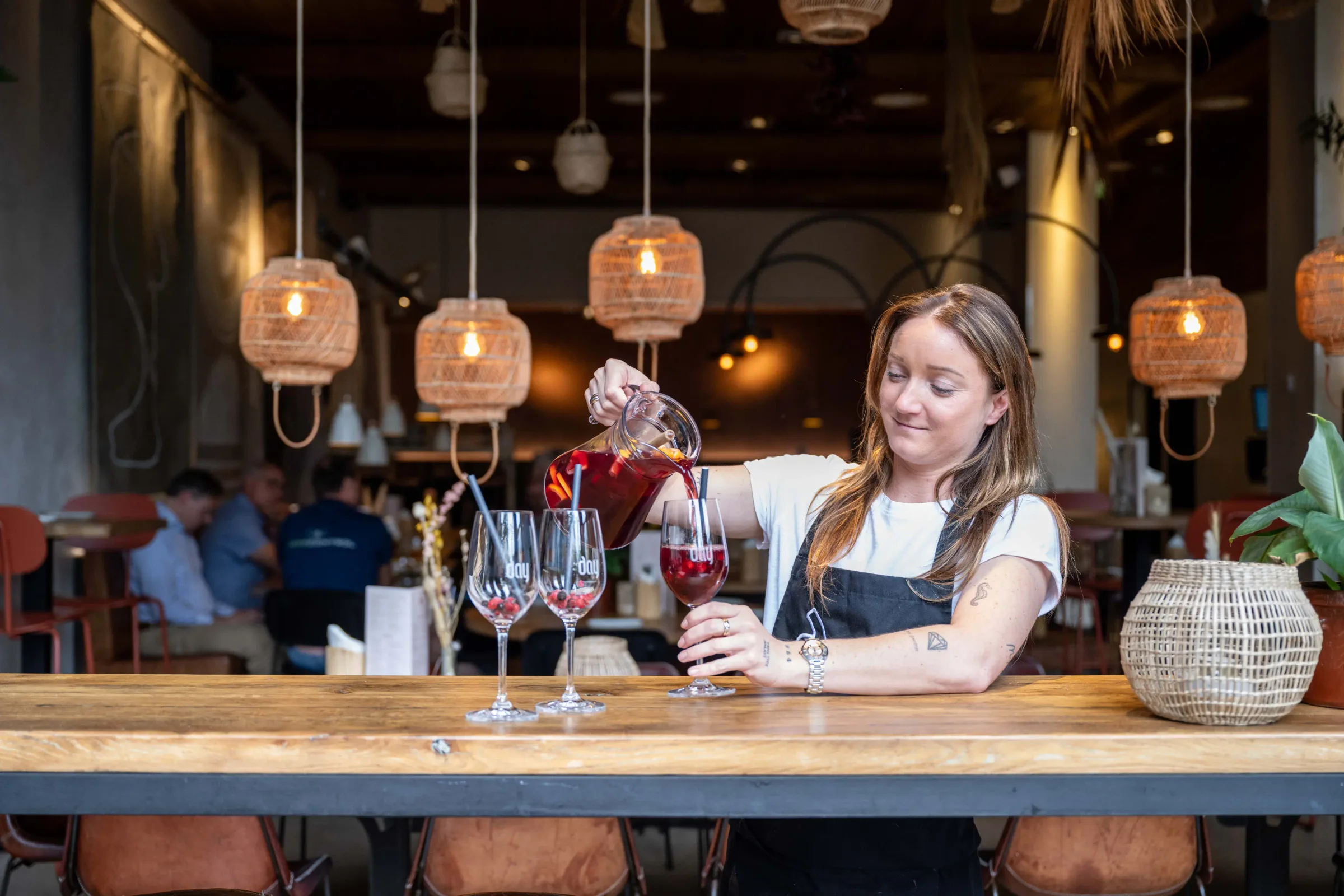 Corporate photo of a woman pouring wine into glasses