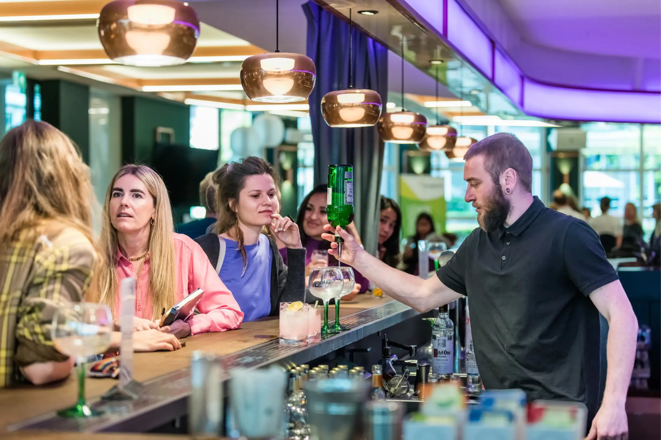 Event photo of a bartender pouring a drink for a woman at the bar