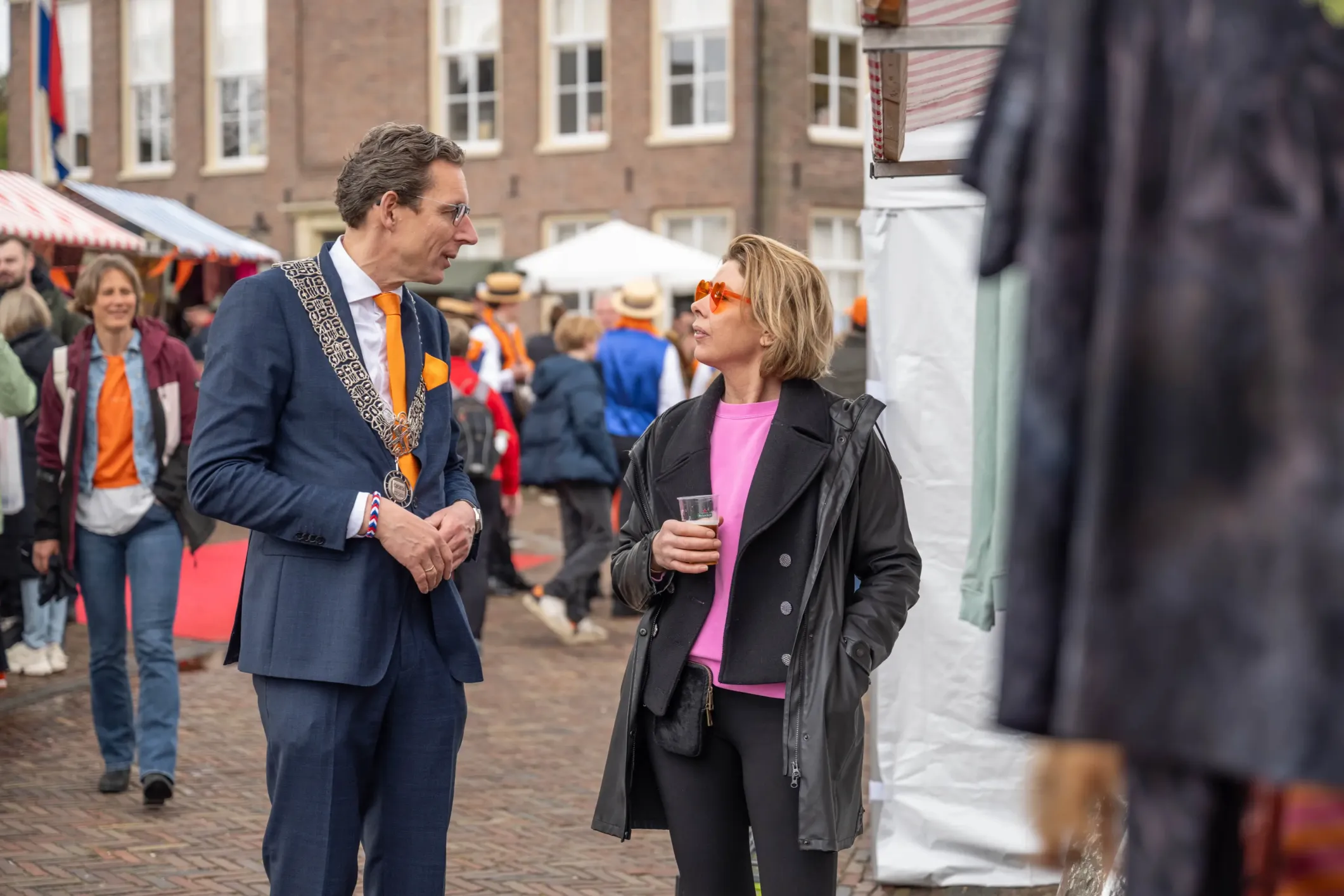 Event photo of the mayor in orange with a woman in a pink shirt