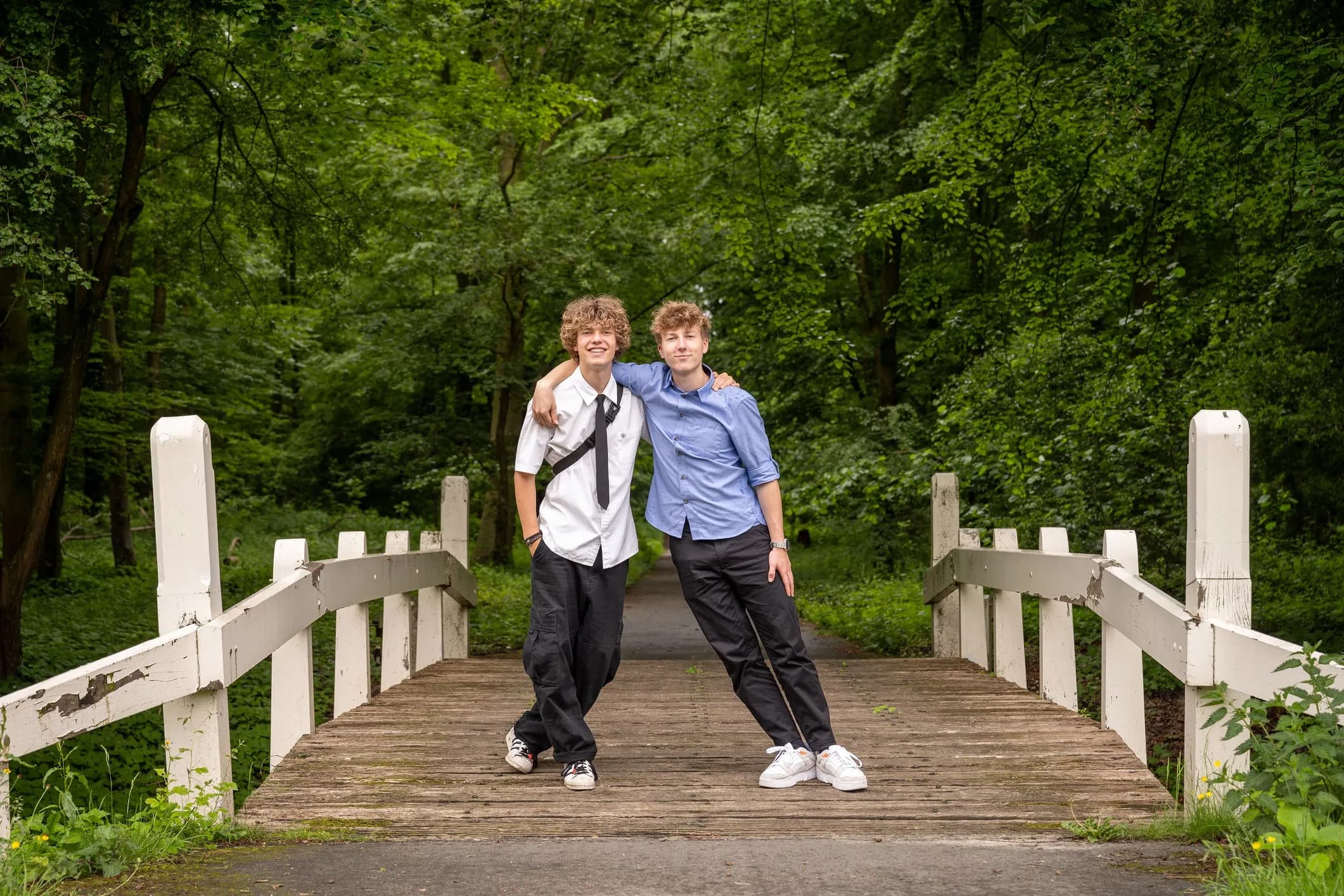 Family photo of two brothers standing on a bridge in the park
