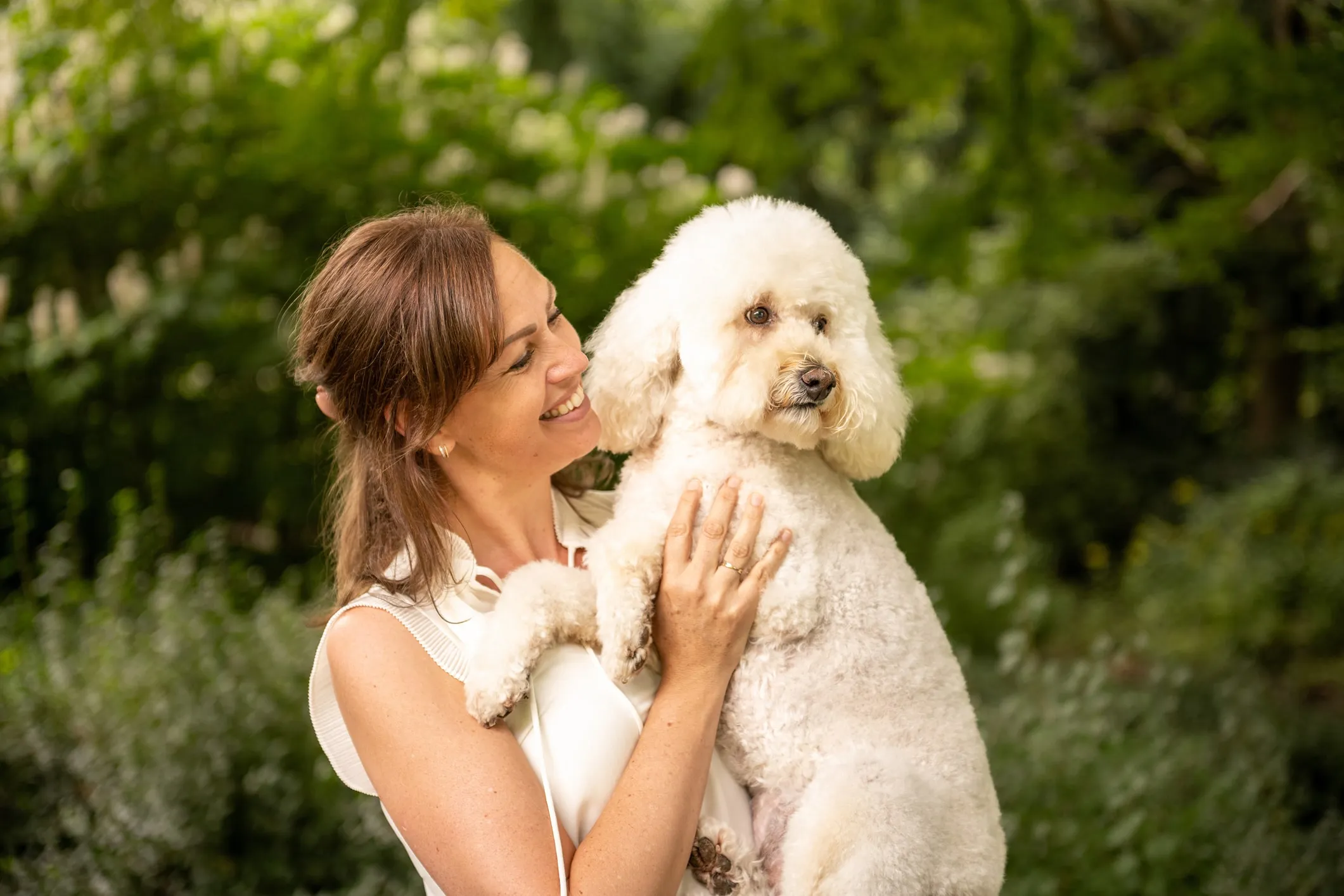 Family photo of a woman carrying her white dog in the park
