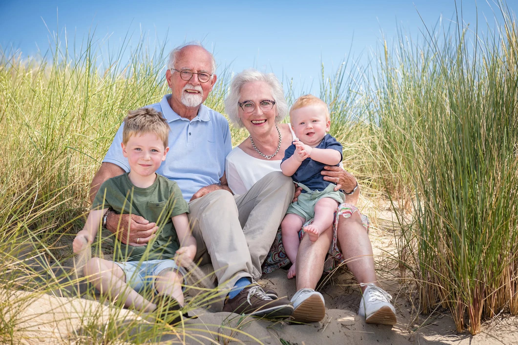 Grandparents sitting with their grandsons among the marram grass on the beach