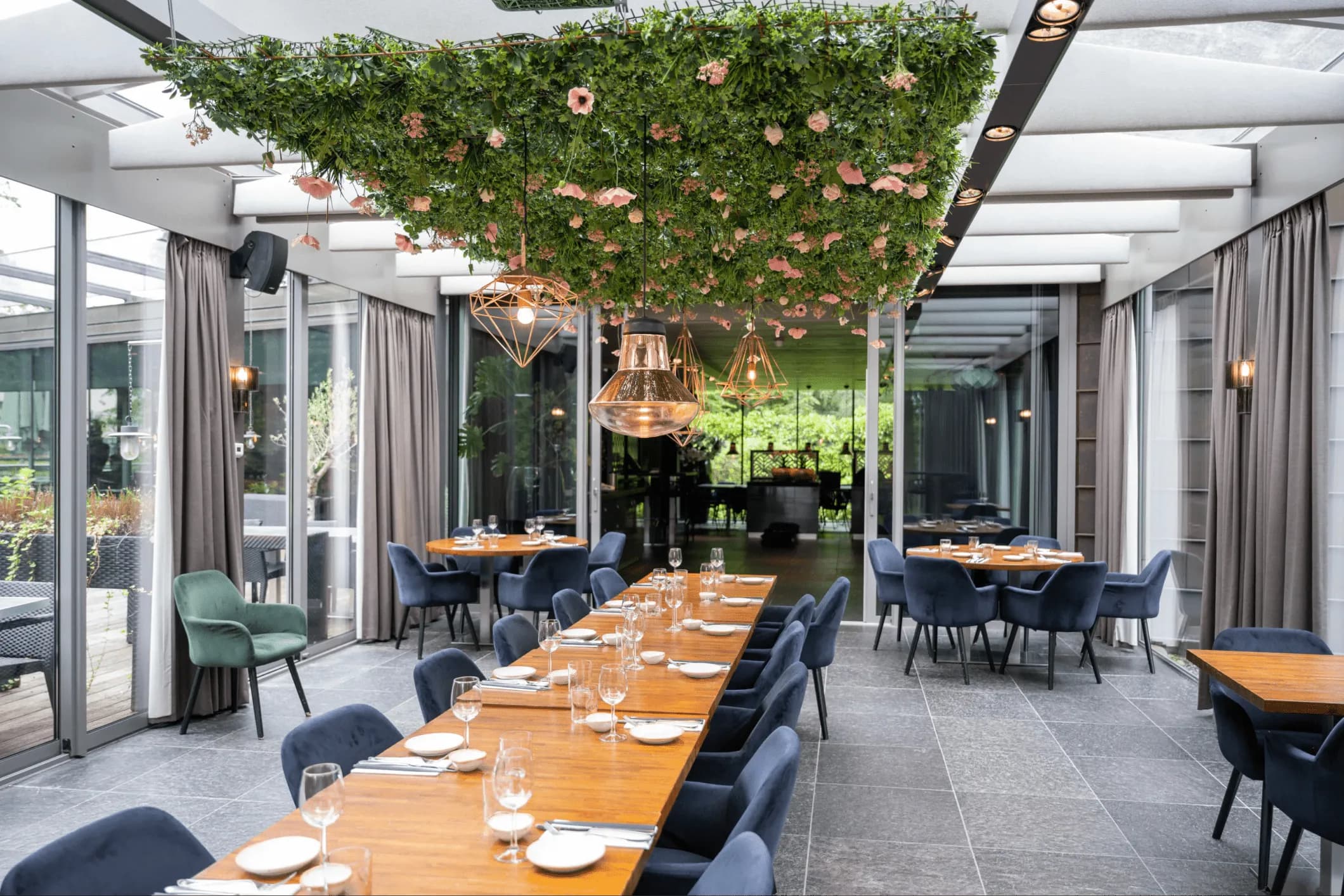 Interior photo of a long dining table with greenery on the ceiling