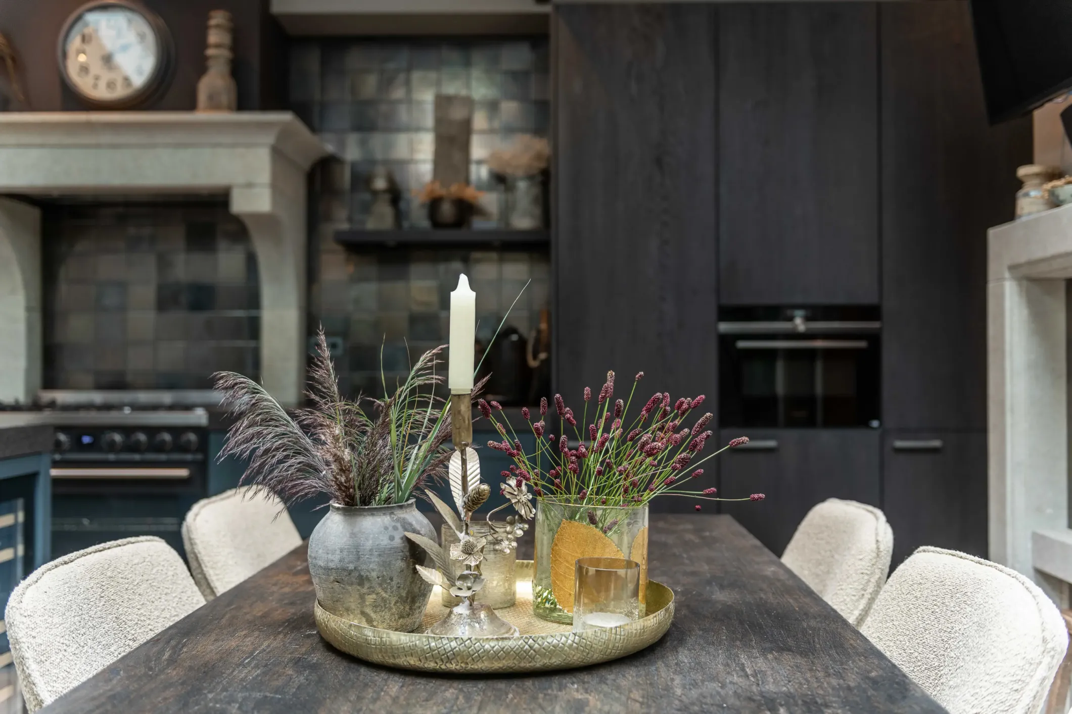 Interior photo of black wooden kitchen cabinets with a grey stone table and white leather chairs