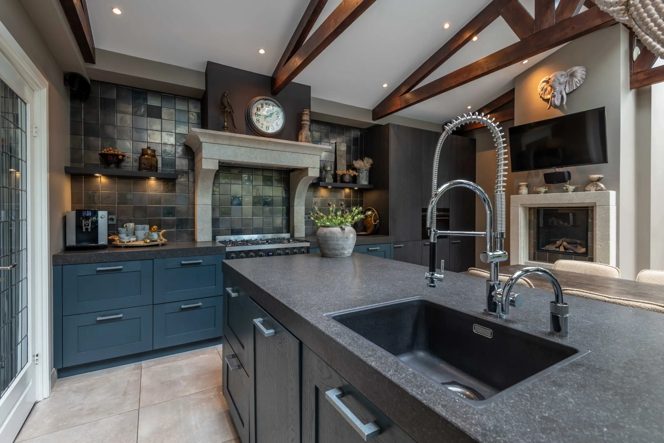 Interior photo of a kitchen with an island, a tap, a blue worktop and a clock