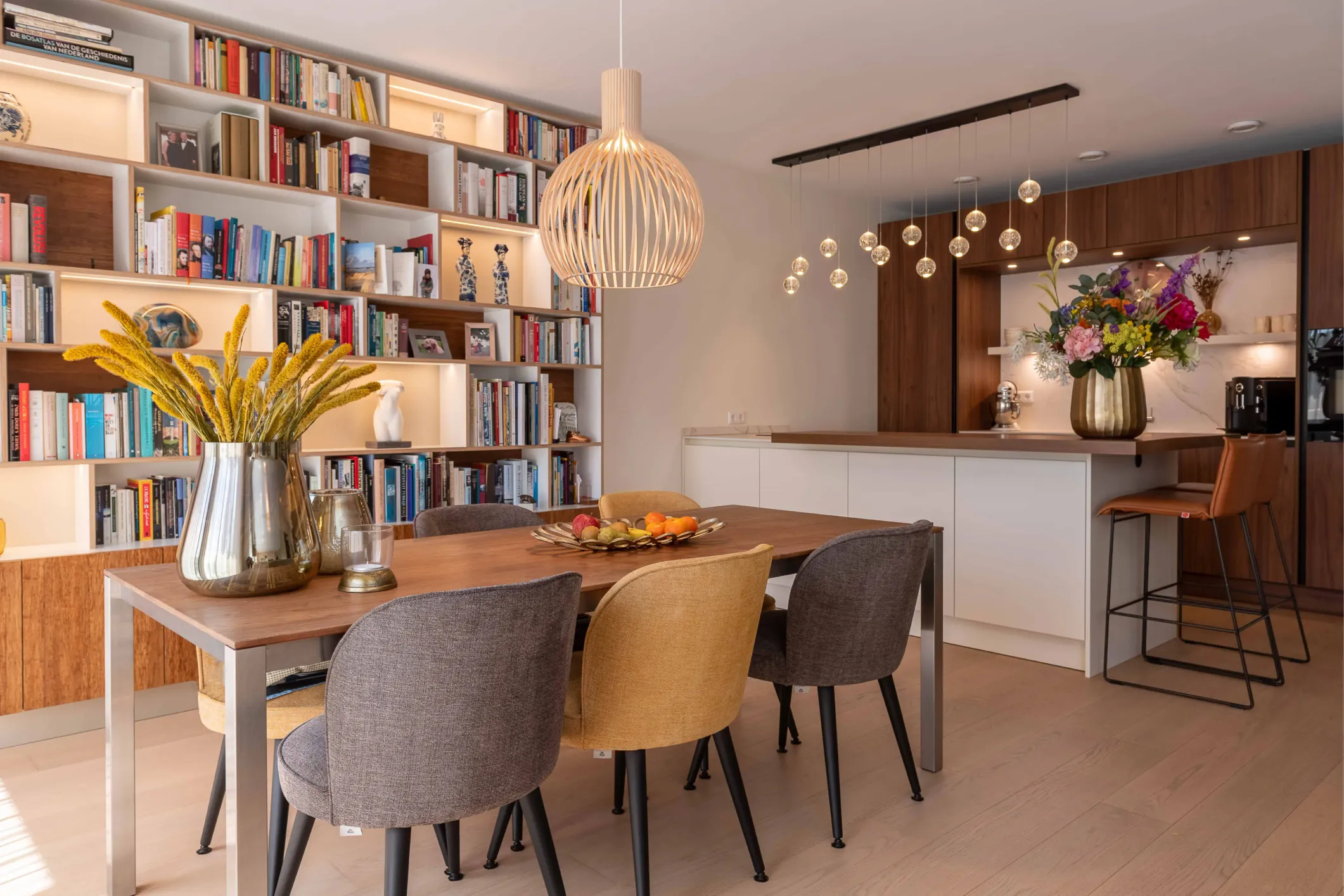 Interior photo of a kitchen with chairs, a large round lamp and a bookcase