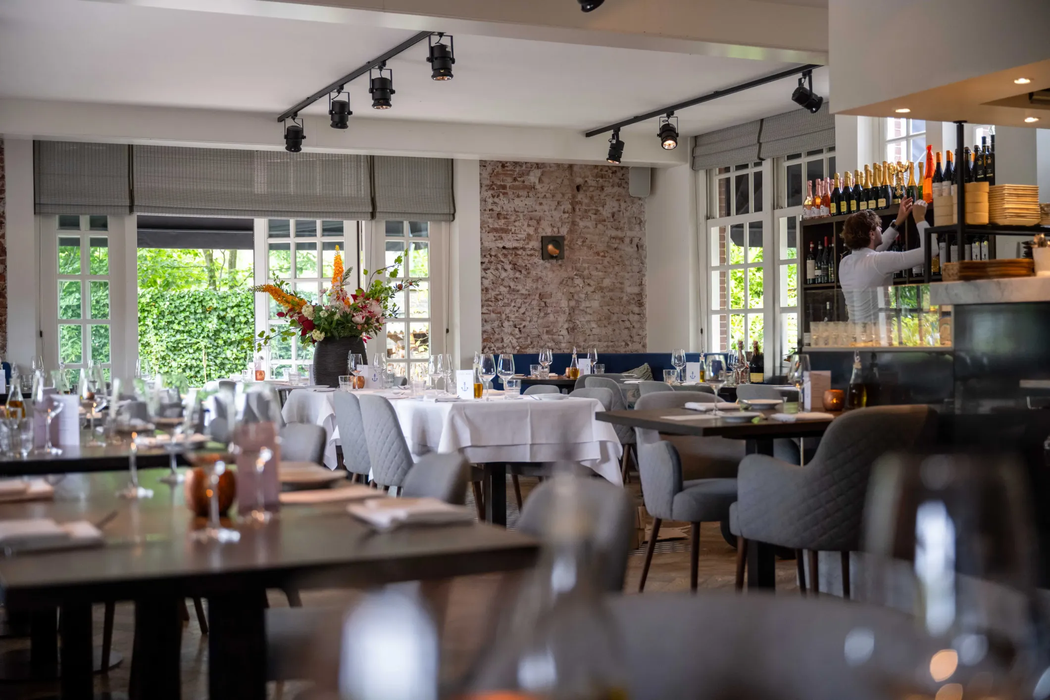 Interior photo of a restaurant with black tables, white upholstery and studio lamps