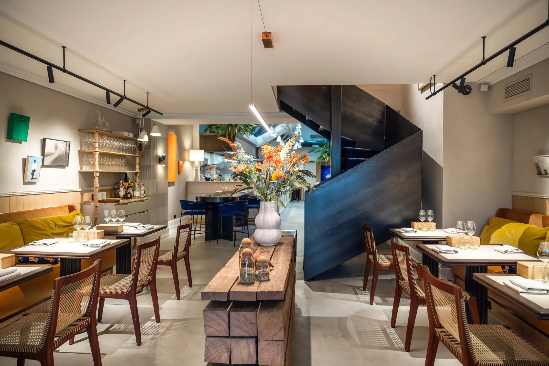 Interior photo of a restaurant with a blue spiral staircase, yellow benches and chairs