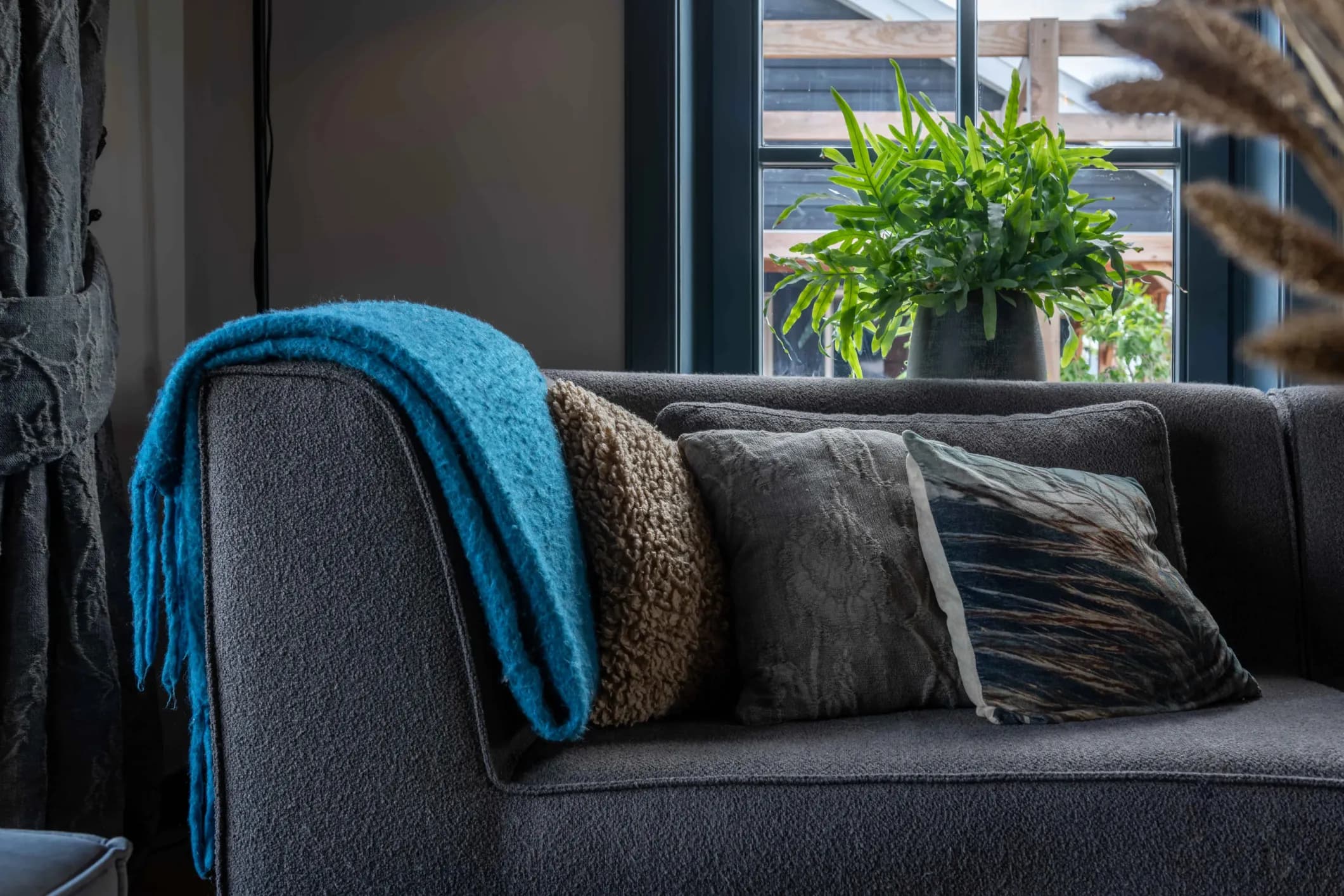 Interior photo of a living room sofa with cushions and a blue throw