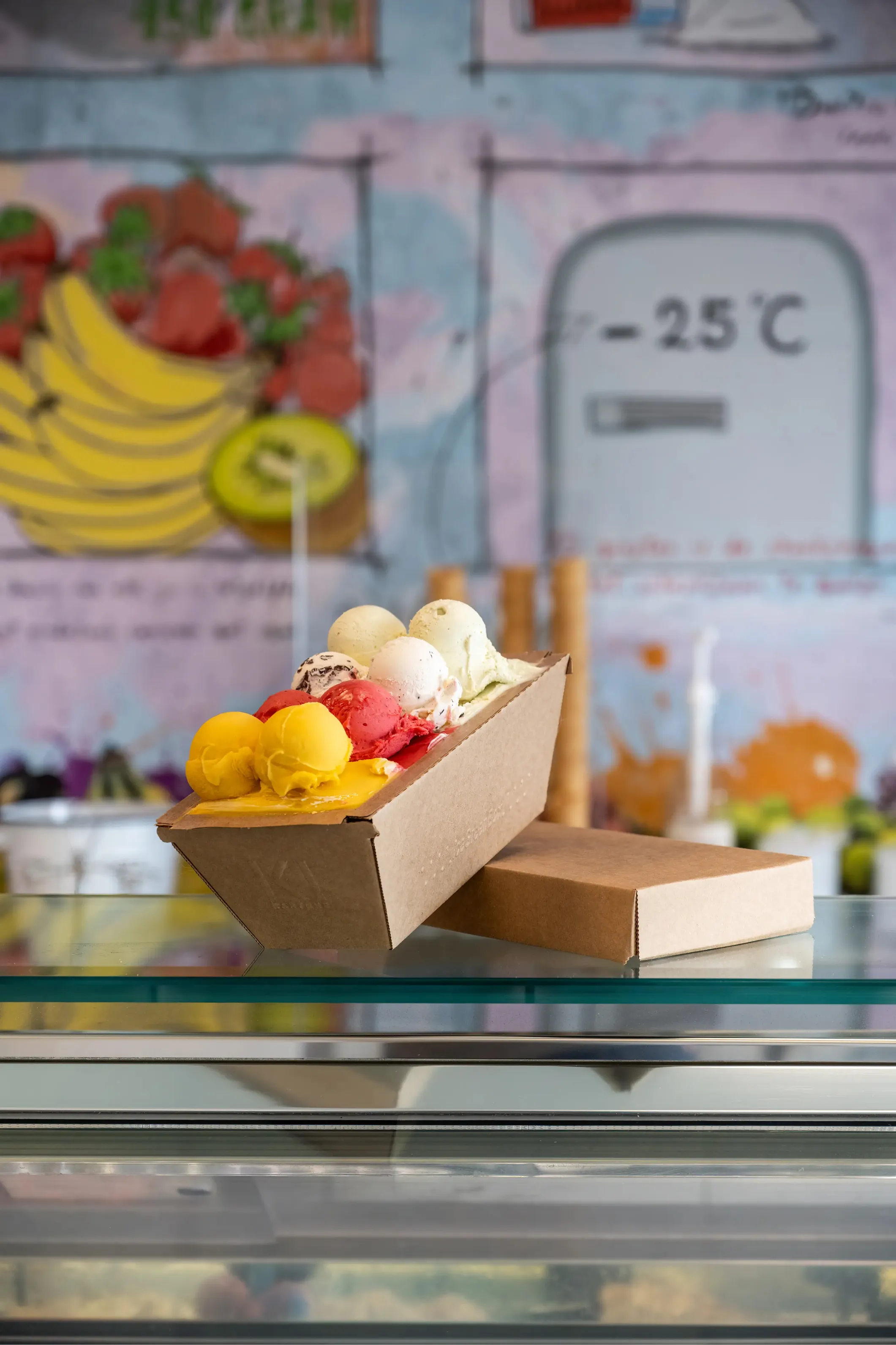 Product photo of scoops of ice cream in a cardboard tub on a glass display counter