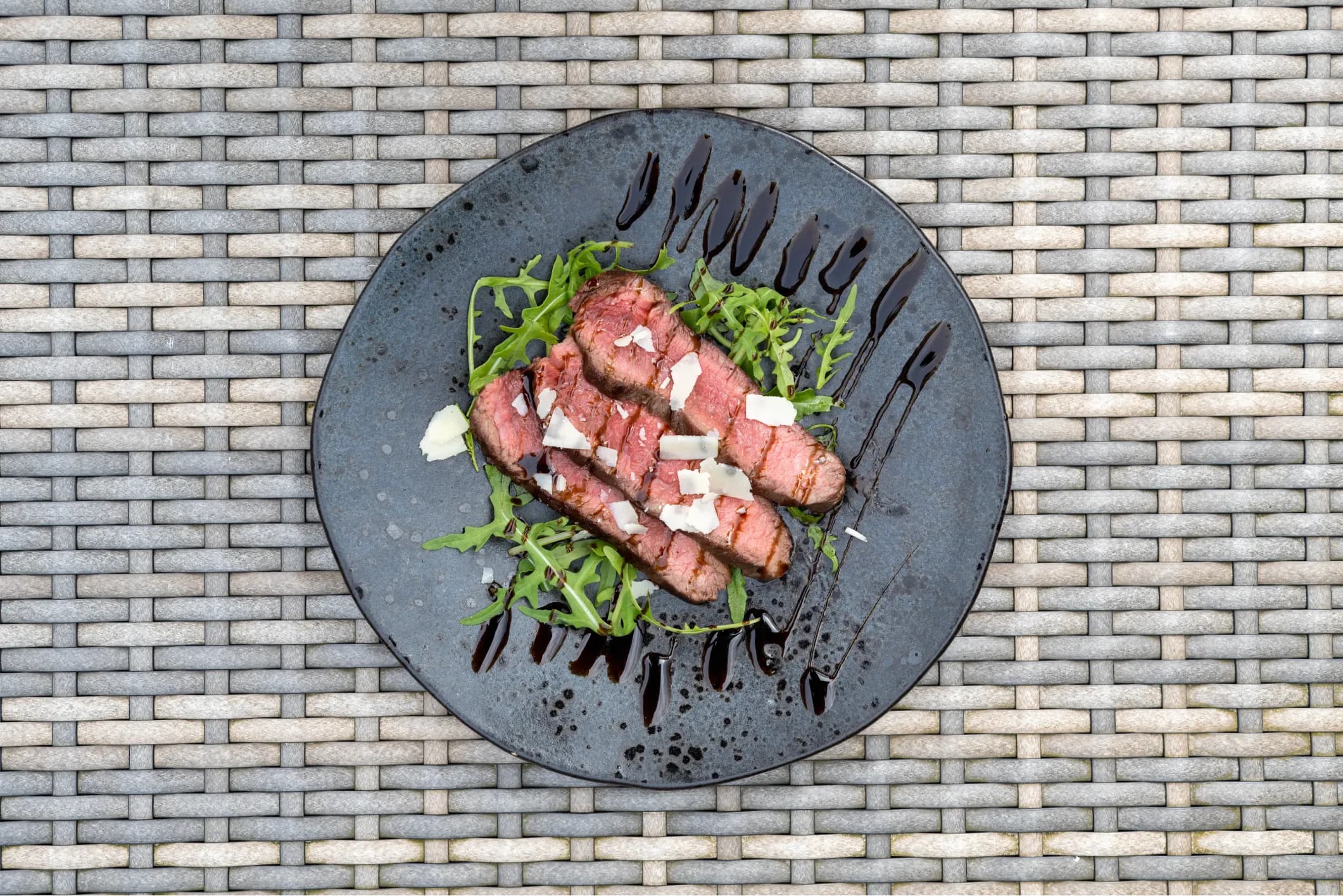 Product photo of steak on a salad with cheese and sauce
