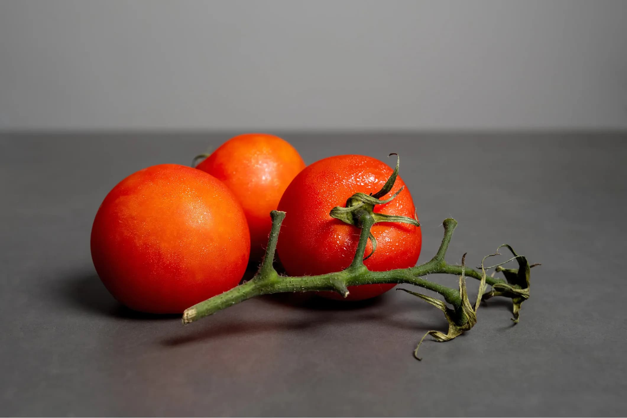 Product photo of red tomatoes on a green vine