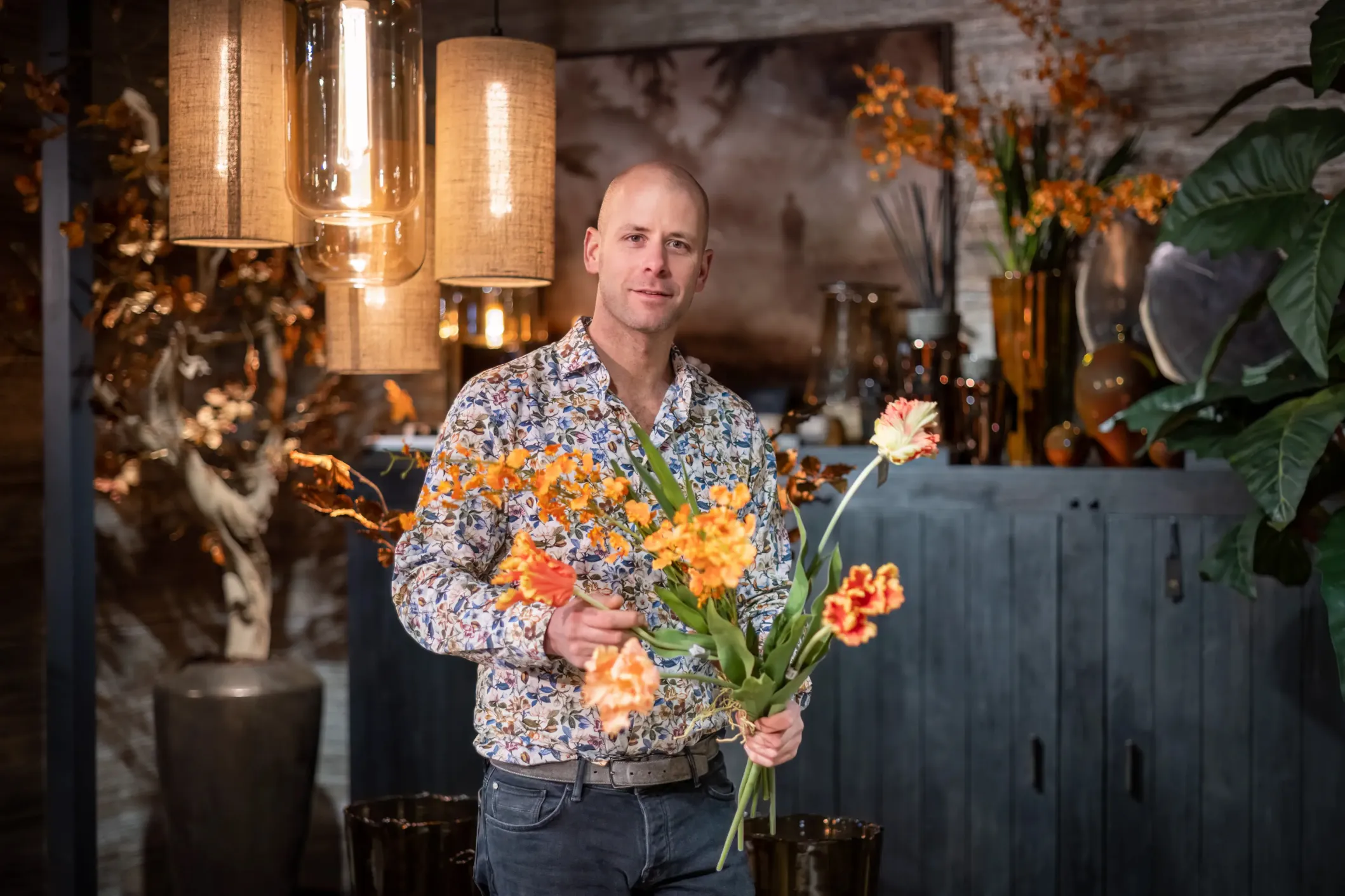 Corporate photo of a florist holding a bouquet of orange flowers in his shop