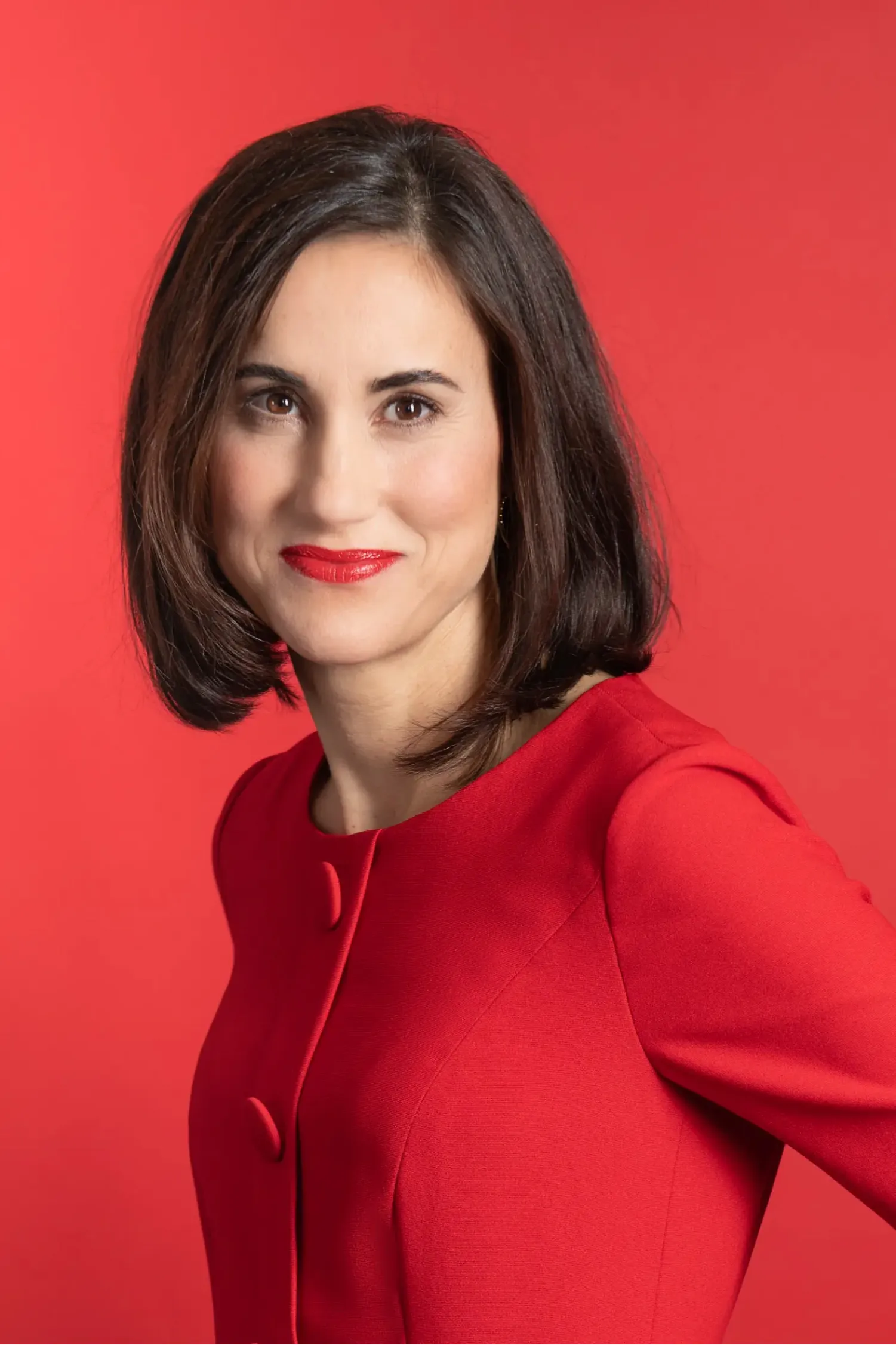 Corporate portrait of a woman in red against a red backdrop