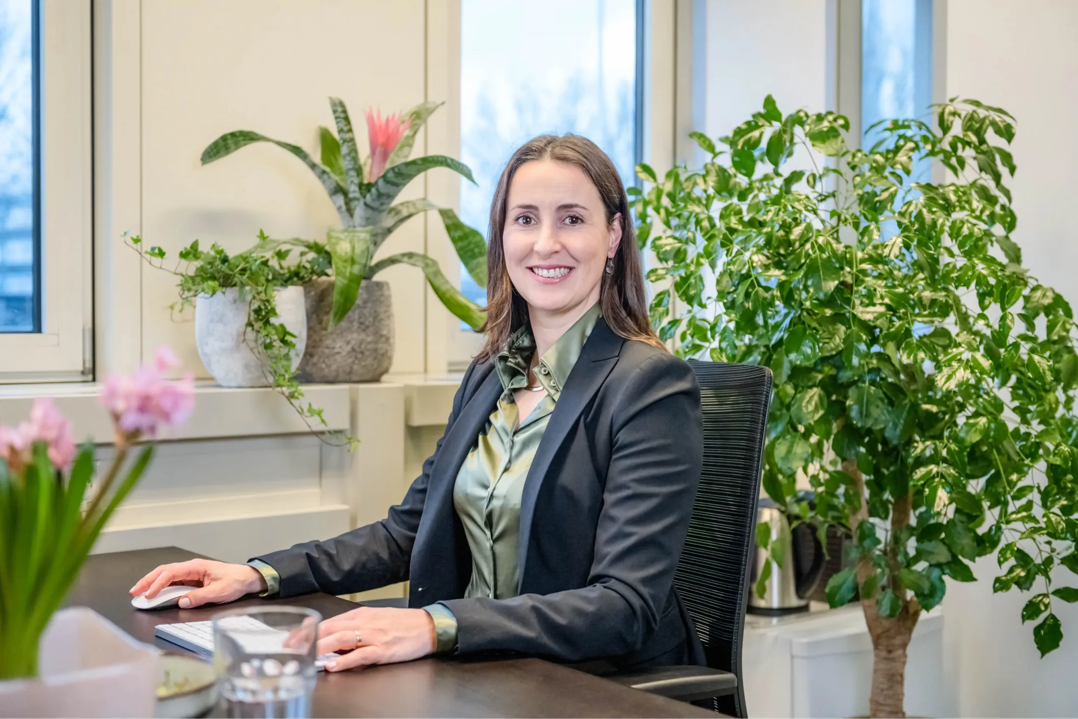 Corporate photo of a smiling woman in a suit at her computer