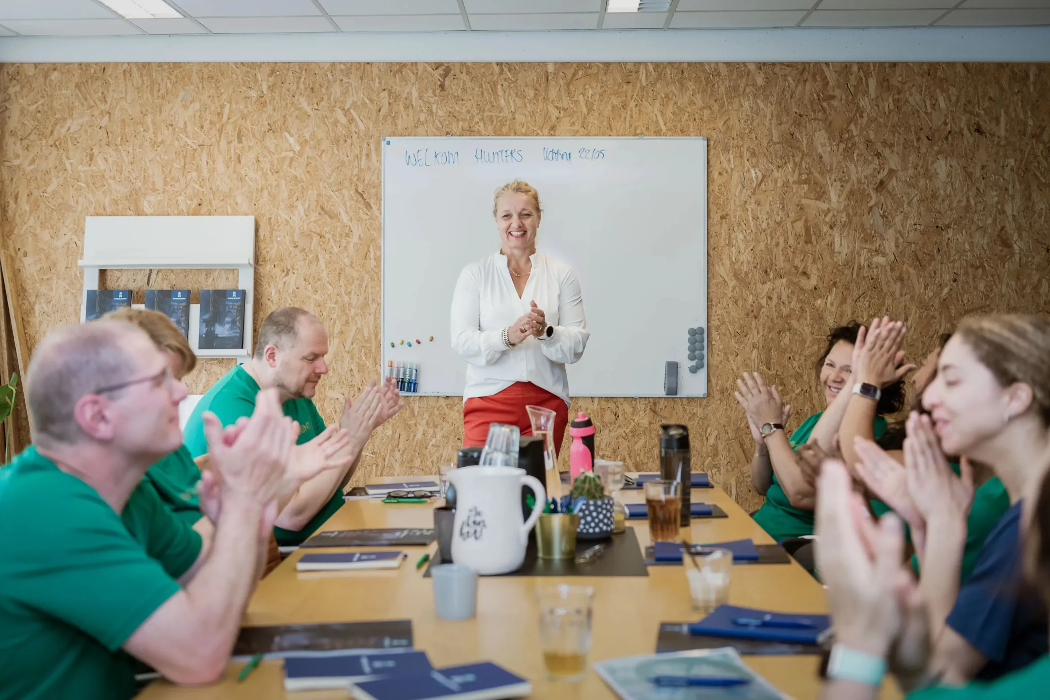 Workshop: a woman at the whiteboard while the team applauds