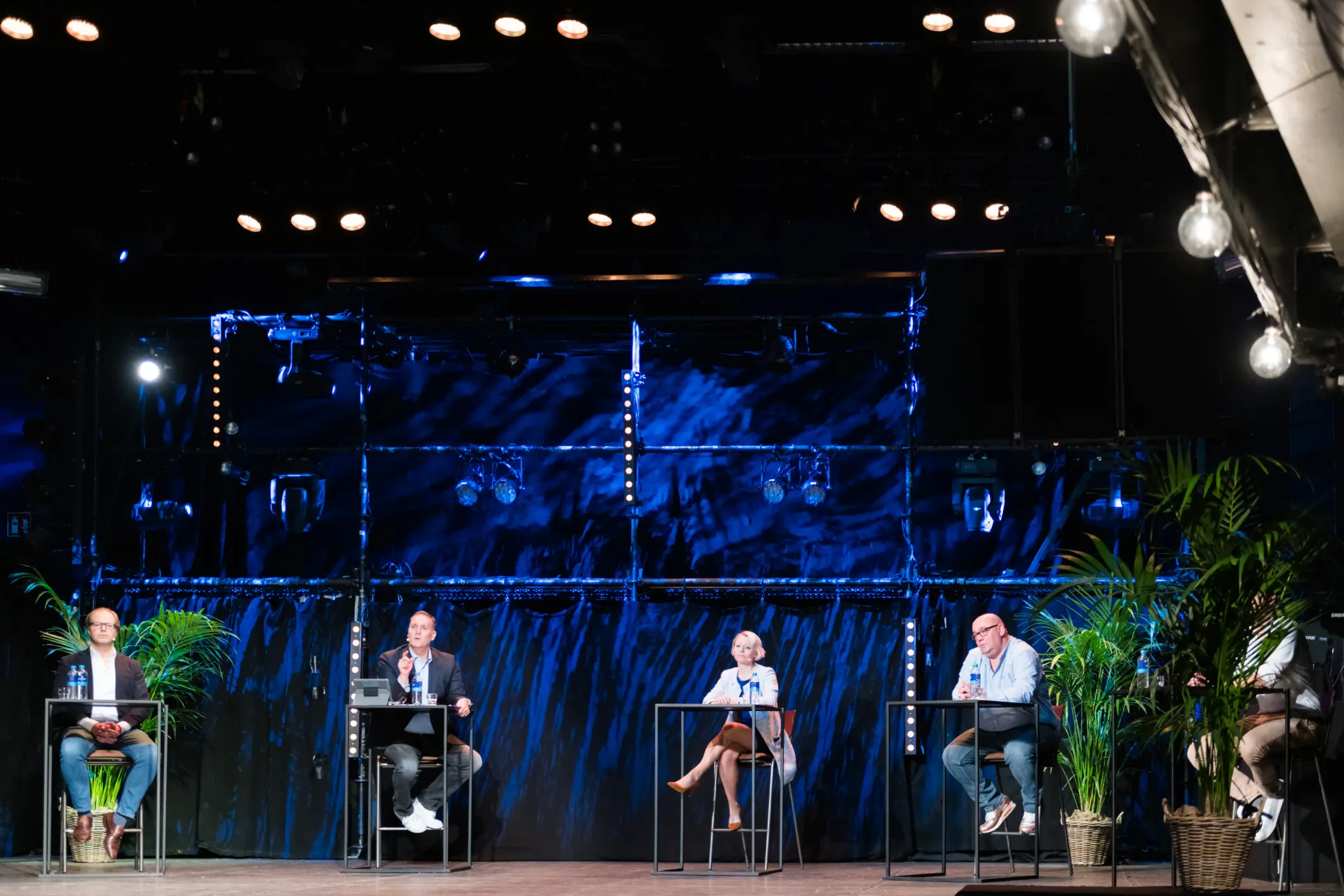 Event photo of a panel discussion on a stage in blue light
