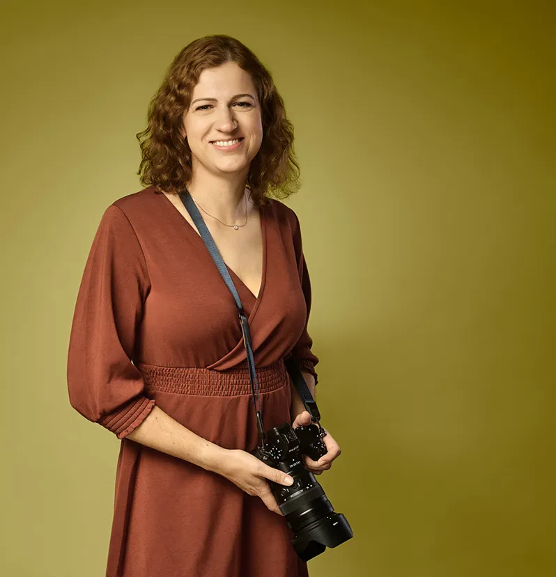 Joanna Vunderink with her camera, in a rust brown dress